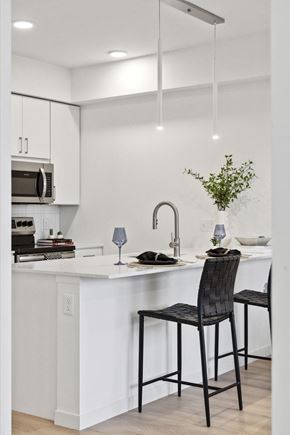 Minneapolis apartment for rent - a kitchen with white cabinets and a white island with two black stools