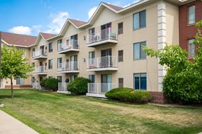Burnsville apartment for rent - an exterior view of an apartment building with a lawn and trees