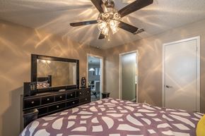 San Antonio apartment for rent - A bedroom with a bed, dresser, mirror, and ceiling fan.