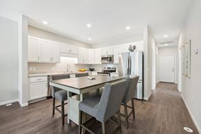 Monticello triplex for rent - a kitchen with white cabinets and a large island with chairs