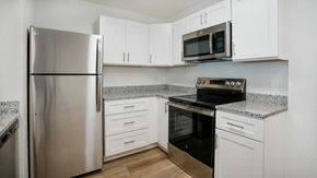 Lake Worth Beach apartment for rent - A kitchen with a stainless steel refrigerator, microwave, oven, and cabinets.