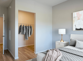 Hopkins apartment for rent - A bedroom with a bed, nightstand, and clothes hanging on a rack.