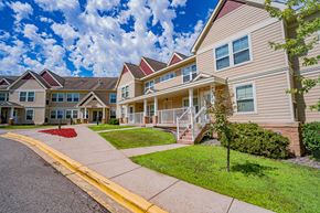 Oakdale apartment for rent - A row of houses with a red flower bed in front of the first house.