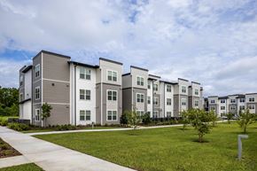 Ocala apartment for rent - Apartment complex with grey and white buildings and green lawns.