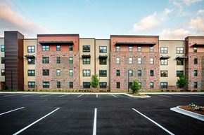 Valdosta apartment for rent - A large parking lot in front of a multi-story brick building.