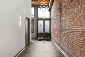 St. Louis apartment for rent - A hallway with a brick wall on one side and a glass door on the other.
