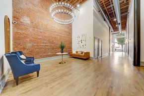St. Louis apartment for rent - A blue chair sits in a room with a brick wall and a chandelier.