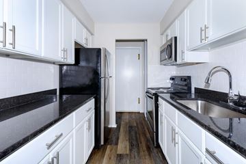 Willoughby apartment for rent - a kitchen with white cabinets and black counter tops and a black refrigerator