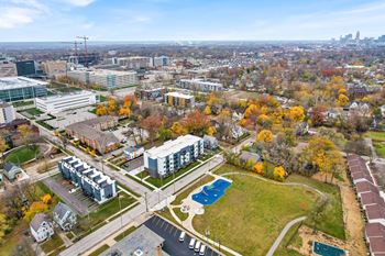 A view of a city from a high vantage point with buildings, trees, and a pool.