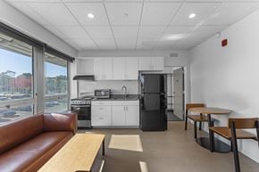 Painesville apartment for rent - A kitchen with white cabinets and a black refrigerator.