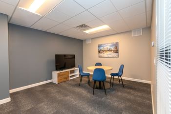 A conference room with a table, chairs, and a television.
