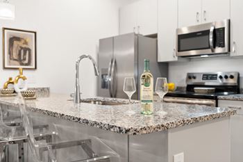 A kitchen with a granite countertop and a wine glass on it.