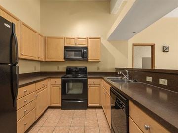 Cleveland apartment for rent - a kitchen with black appliances and wooden cabinets