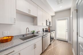 Cleveland townhouse for rent - A modern kitchen with white cabinets and a granite countertop. at Park Lamont Townhomes Apartments, Cleveland, Ohio