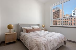Cleveland apartment for rent - A bedroom with a large bed and a window overlooking a cityscape.