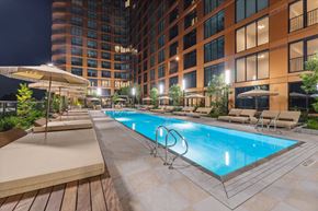 Atlanta apartment for rent - A large outdoor swimming pool surrounded by lounge chairs and umbrellas.