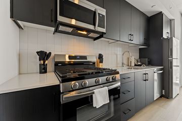 Houston apartment for rent - A modern kitchen with a black stove top oven and black cabinets.