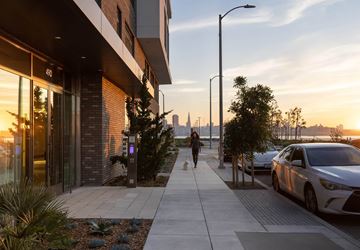 San Francisco apartment for rent - A woman walking her dog on a sidewalk next to a parked car.