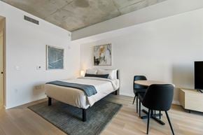 Houston apartment for rent - A bedroom with a bed, chair, and painting on the wall.