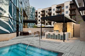 Phoenix apartment for rent - a swimming pool with tables and umbrellas in front of an apartment building