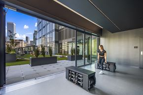 Seattle apartment for rent - a woman sits on a suitcase in front of a large glass window
