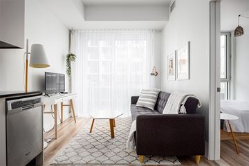 Montréal apartment for rent - A living room with a grey couch and a television.