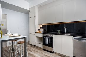Montréal apartment for rent - A modern kitchen with a black countertop and stainless steel appliances.