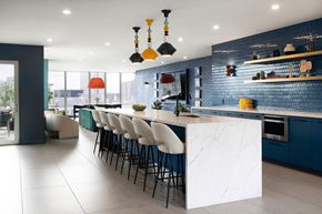 Montréal apartment for rent - A modern kitchen with a long white island and bar stools.
