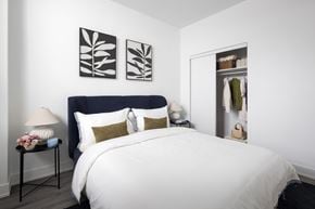 Toronto apartment for rent - A bedroom with a large bed and a nightstand with a lamp.