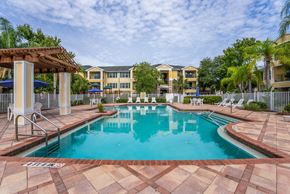 Largo apartment for rent - A large swimming pool surrounded by a tiled patio and lounge chairs.