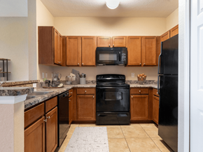 Melbourne apartment for rent - A kitchen with black appliances and wooden cabinets.