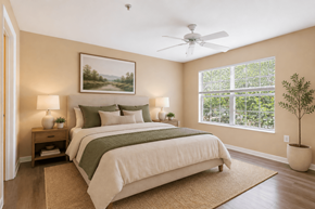 Tampa apartment for rent - A bedroom with a large bed, a ceiling fan, and a painting on the wall.