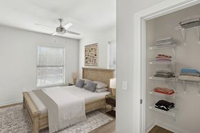 Norfolk apartment for rent - A bedroom with a bed, a fan, and a closet with clothes.