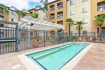 Hayward apartment for rent - A pool surrounded by a black fence and a building in the background.