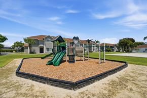 Homestead apartment for rent - A playground with a green slide and a brown sandbox.