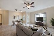 Ocala apartment for rent - A living room with a grey couch and a ceiling fan.