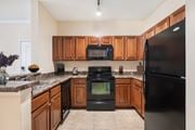 Ocala apartment for rent - A kitchen with black appliances and wooden cabinets.