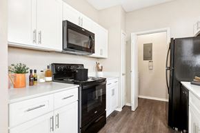 Austin apartment for rent - a kitchen with white cabinets and black appliances and a black refrigerator at Canyon Creek, Austin, TX