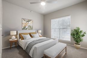 Austin apartment for rent - A bedroom with a bed, two lamps, a bench, and a plant.