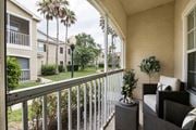 Ocala apartment for rent - A balcony with a chair and a table with a plant on it.