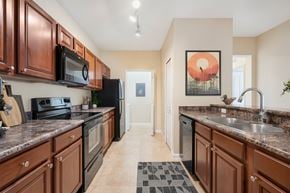 Ocala apartment for rent - A kitchen with brown cabinets and a black refrigerator.