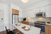 Waltham apartment for rent - a kitchen with stainless steel appliances and a white table at The Merc, Waltham, MA, 02453