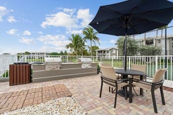 A patio with grills, a table and chairs, and an umbrella