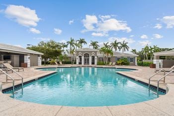 A swimming pool with palm trees and a house in the background