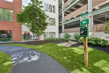 A walkway in front of an apartment building with a green pedestrian crossing sign