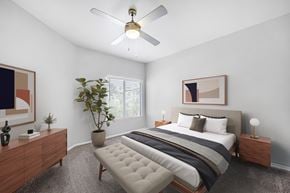 Albuquerque apartment for rent - A bedroom with a large bed, a ceiling fan, and a potted plant.