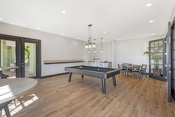 A room with a pool table and a dining table.