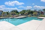 Plant City apartment for rent - A swimming pool surrounded by a concrete deck and a residential area in the background.