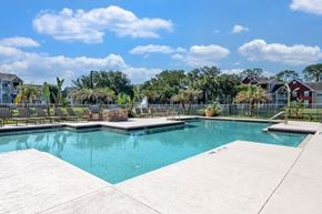 Plant City apartment for rent - A swimming pool surrounded by a concrete deck and a residential area in the background.