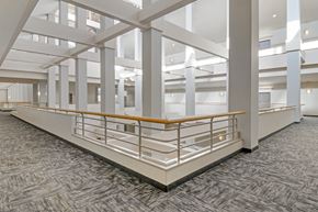 Enfield apartment for rent - A large open space with a carpeted floor and a series of white columns.